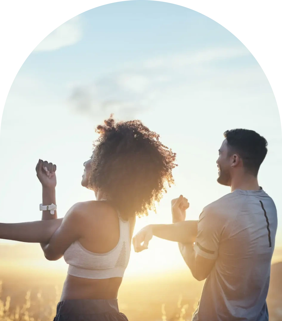Two people dancing outdoors during sunset, enjoying the moment.