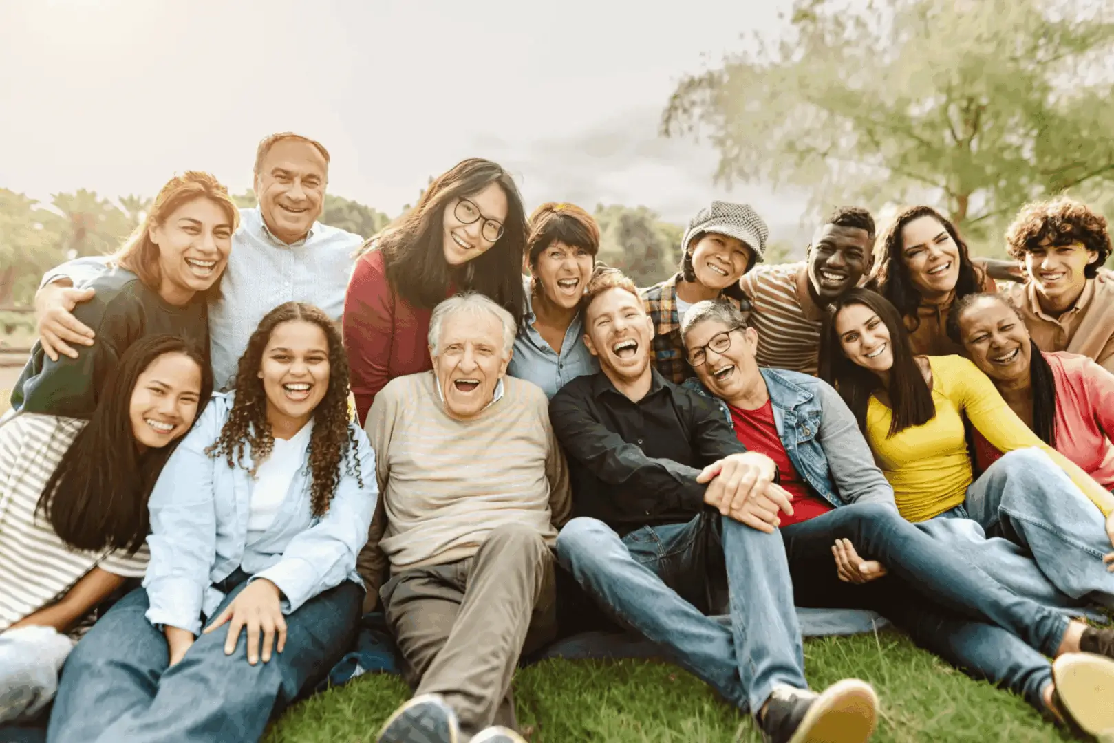 A diverse group of friends happily posing outdoors on grass.